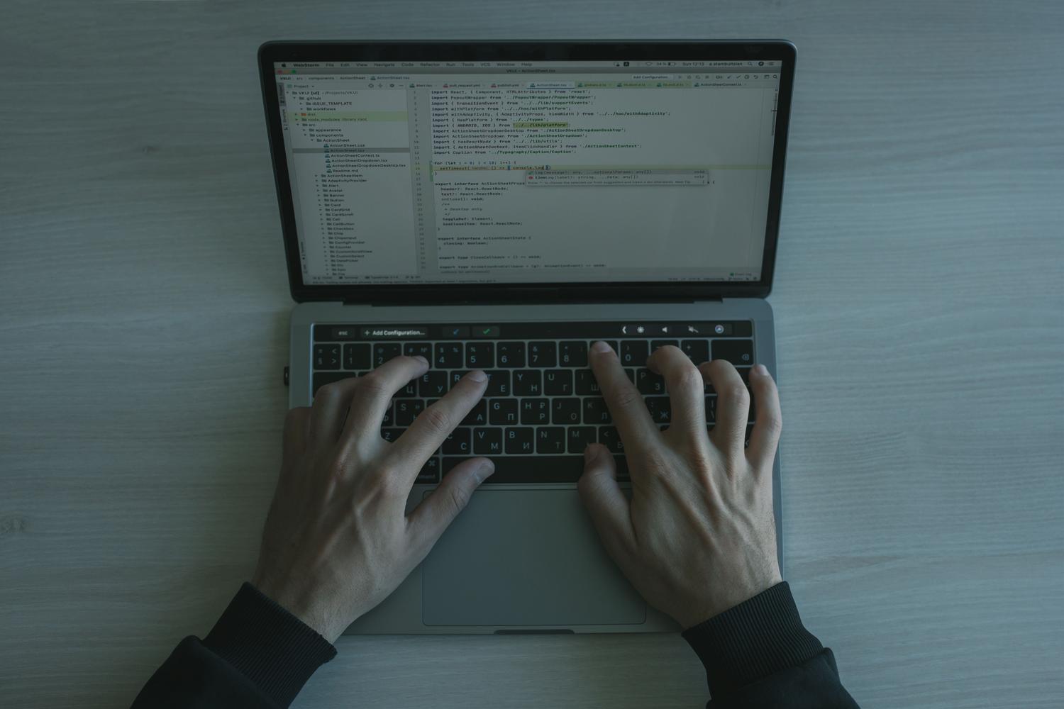 Persona trabajando en un MacBook con código en pantalla, representando la ejecución de comandos técnicos en la Terminal para reparar permisos.