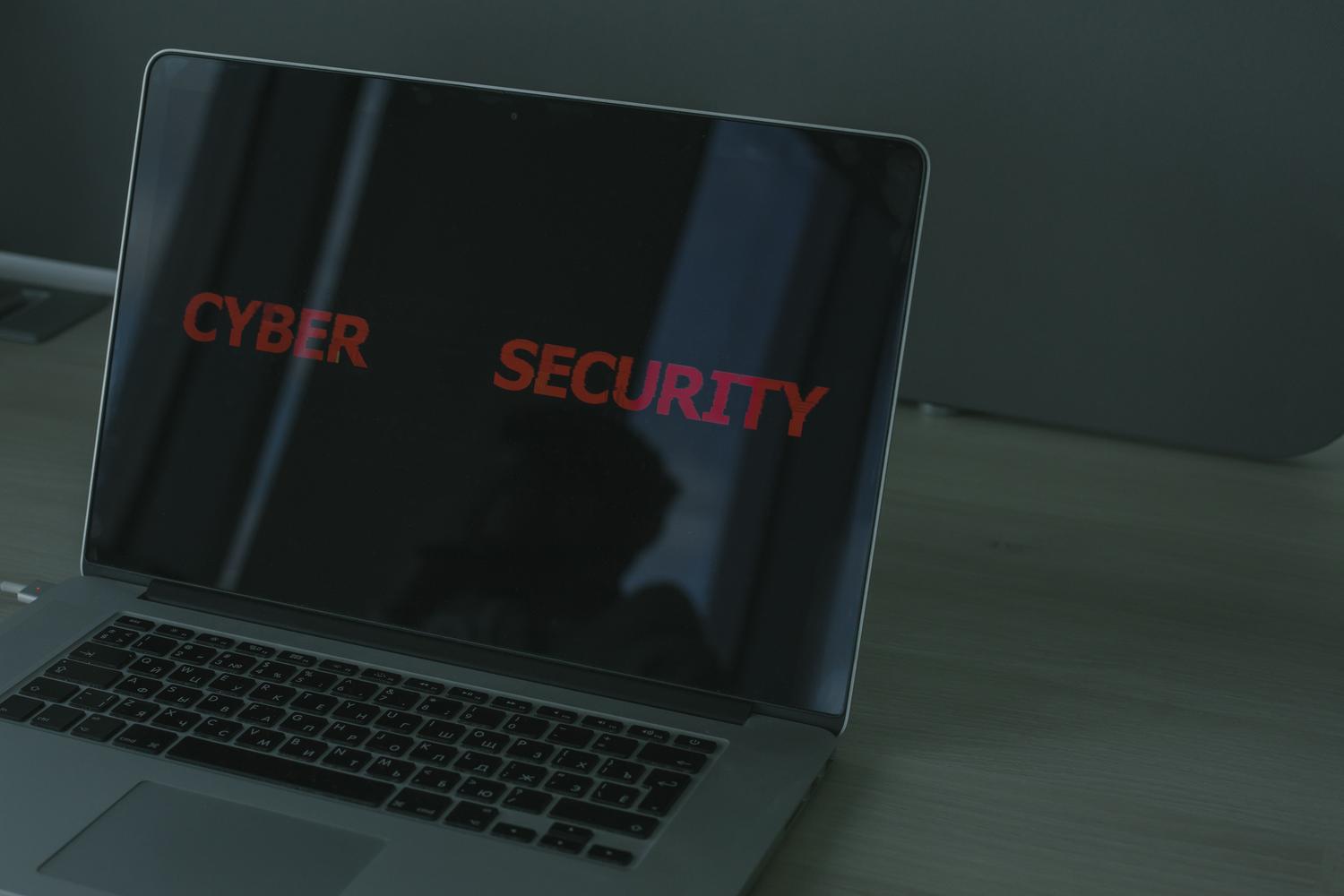 Primer plano de un MacBook con el texto 'CYBER SECURITY' en pantalla, representando la seguridad y los permisos del sistema macOS.